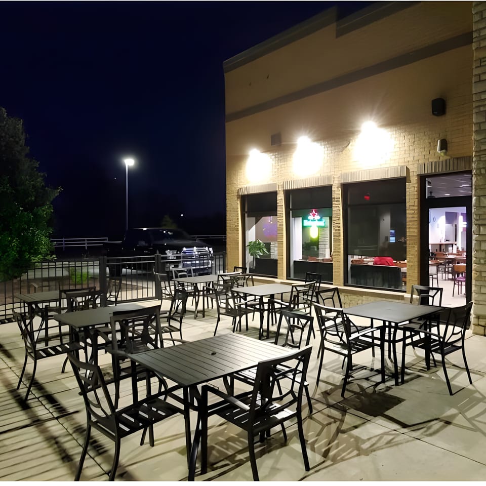 Seafood Palace's outdoor patio at night, with empty tables and chairs under warm lighting.