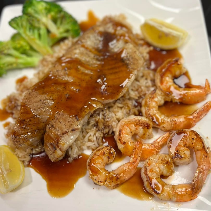 Seafood Palace's grilled fish and shrimp with rice, broccoli, and lemon on a white plate.