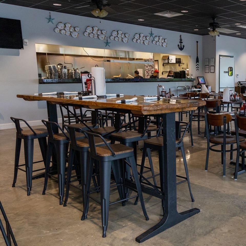 Seafood Palace dining area with a long communal table, bar stools, and an open kitchen.